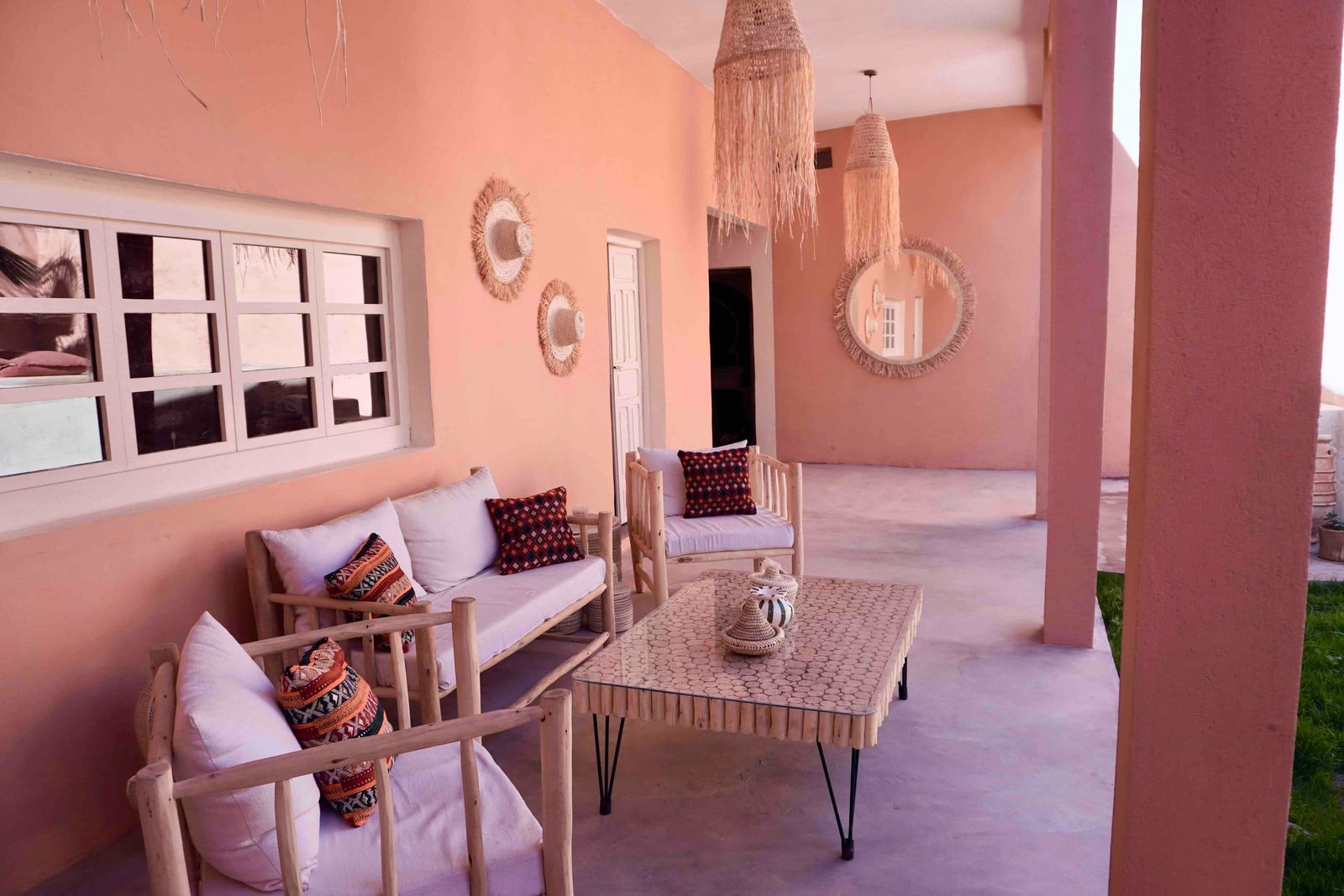 Le salon de jardin abrité sous la terrasse couverte, banquettes et miroirs en osier